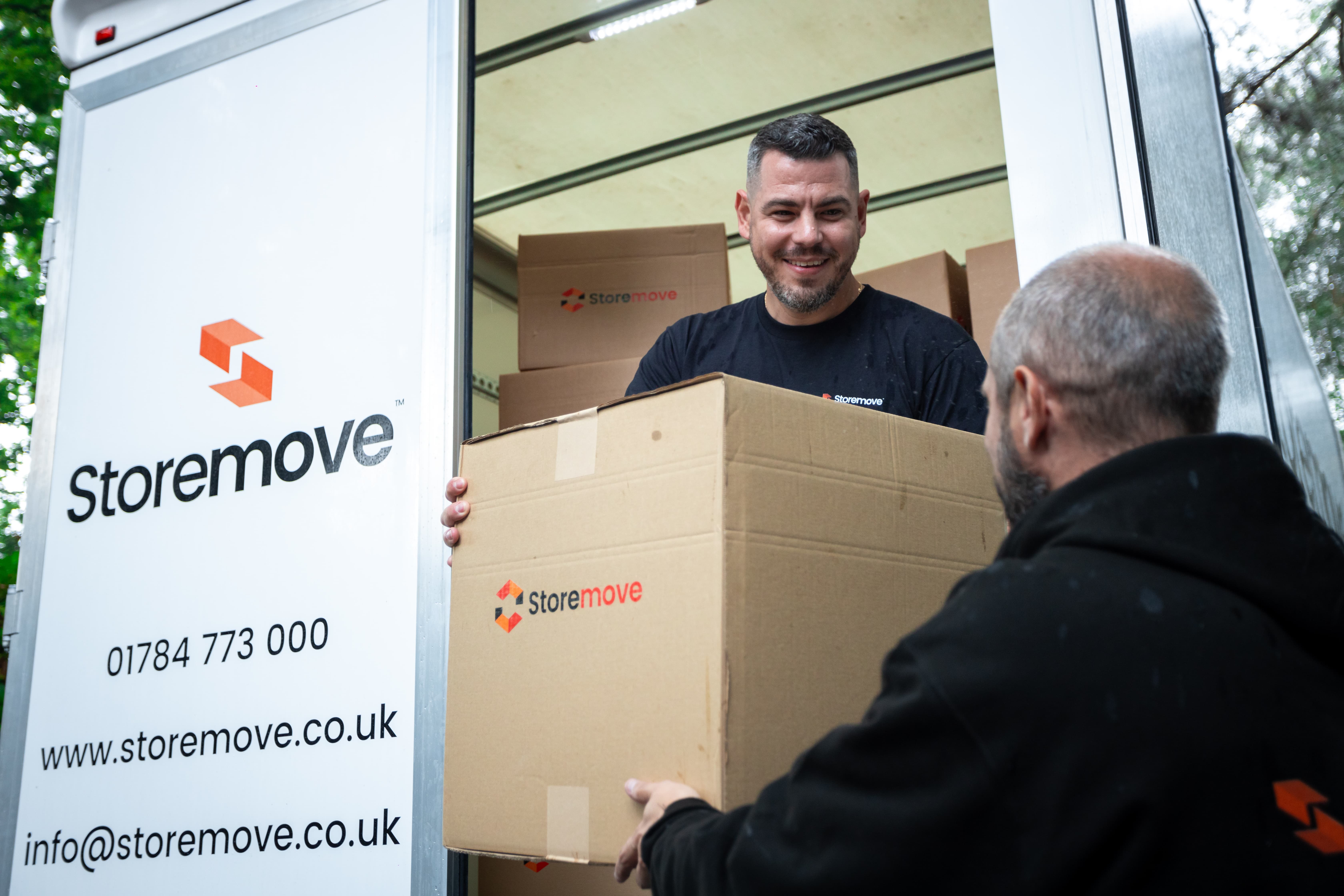 Storemove team member handling a moving box from branded removal van for home or office relocation